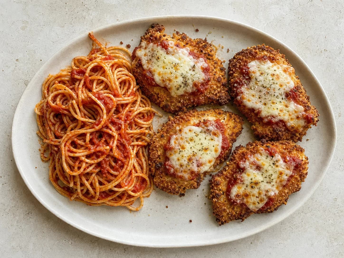 Overhead view of air-fryer chicken parmesan & tomato pasta, served as a family dinner.