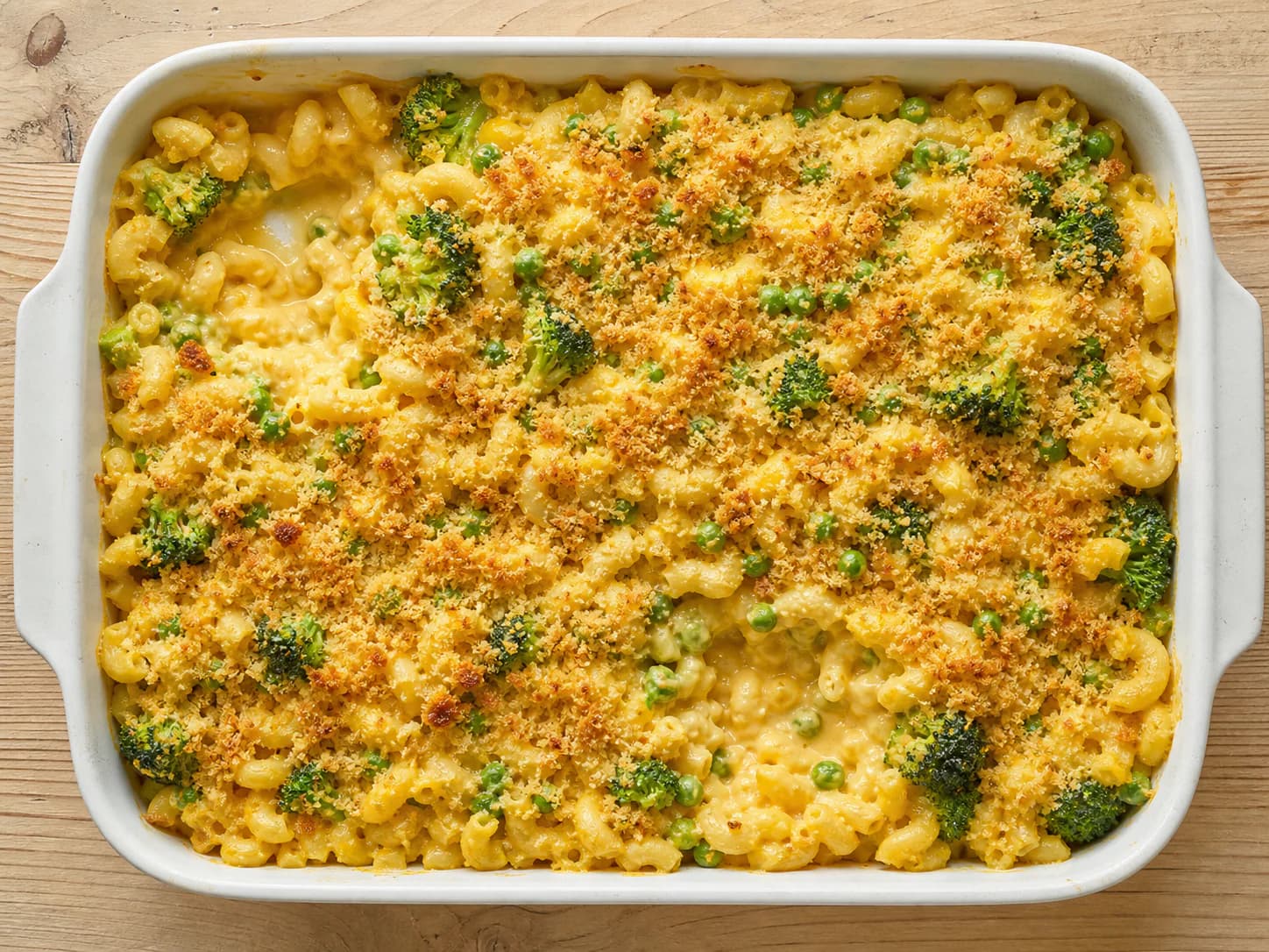 Baked cheddar macaroni with green peas, broccoli and a lightly browned breadcrumb top.