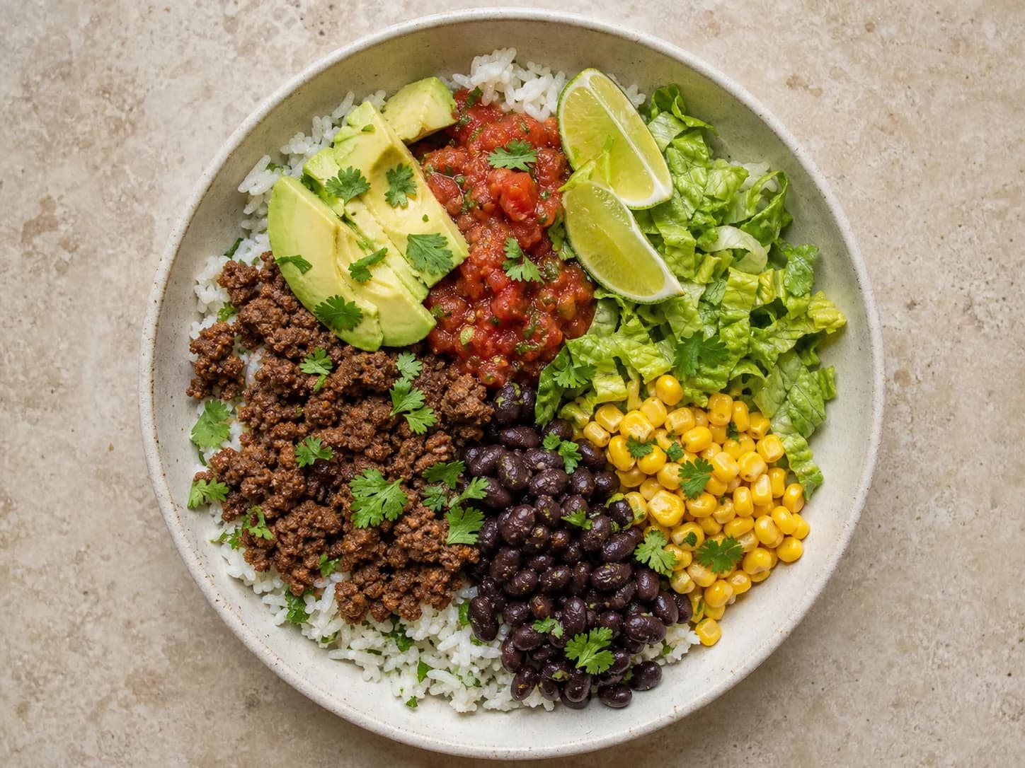 Overhead view of beef burrito rice bowls, served as a family dinner.