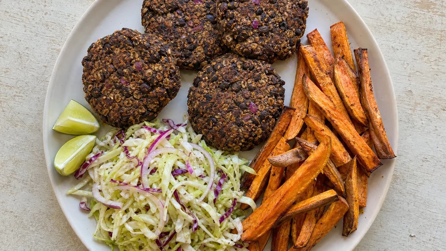 Overhead view of black-bean burger patties & oven fries, served as a family dinner.