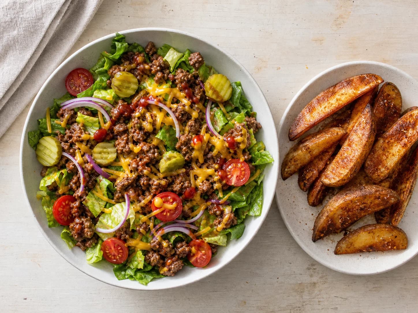 Overhead view of cheeseburger bowls & oven wedges, served as a family dinner.