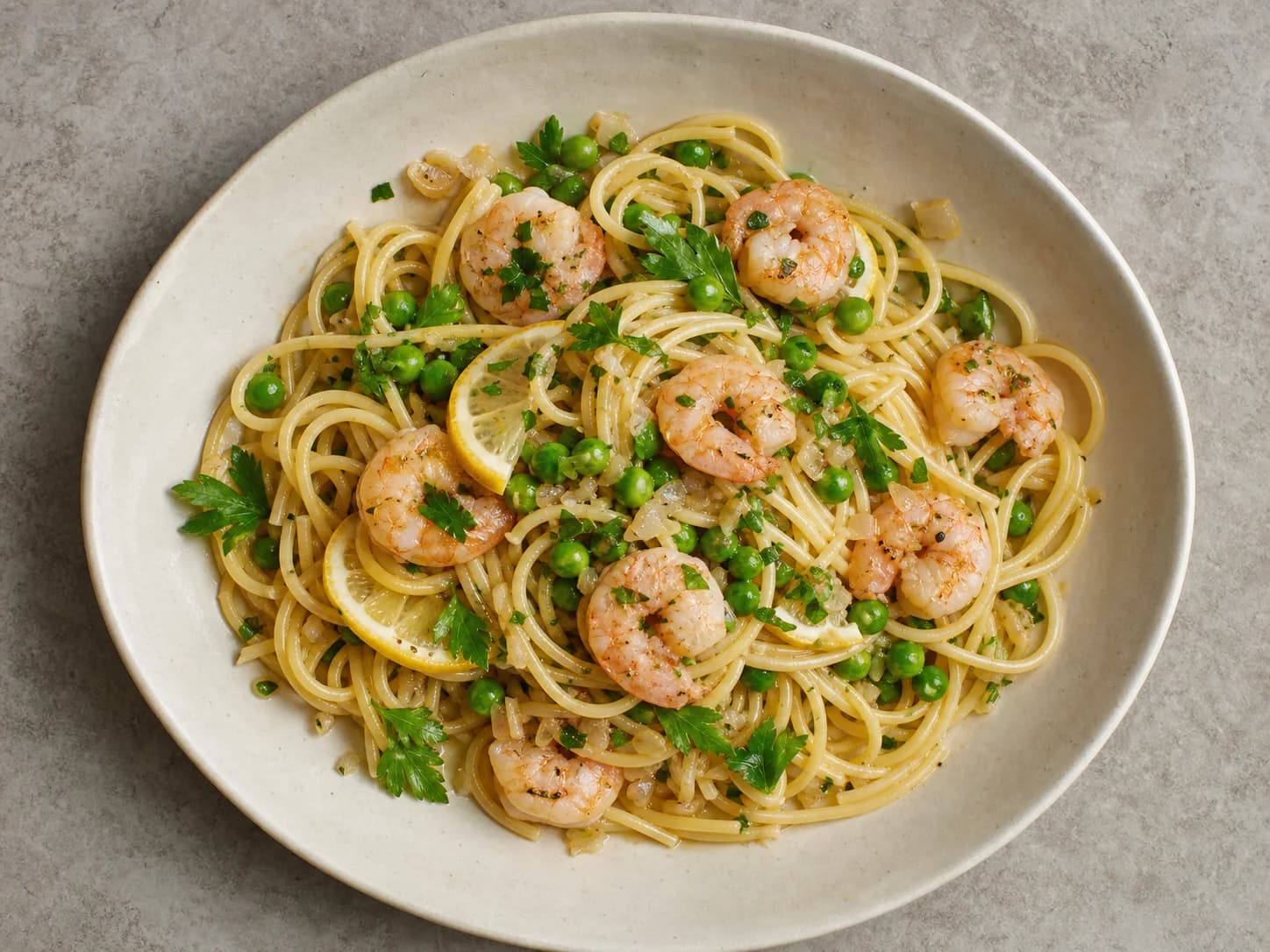 Overhead view of garlic shrimp spaghetti & peas, served as a family dinner.