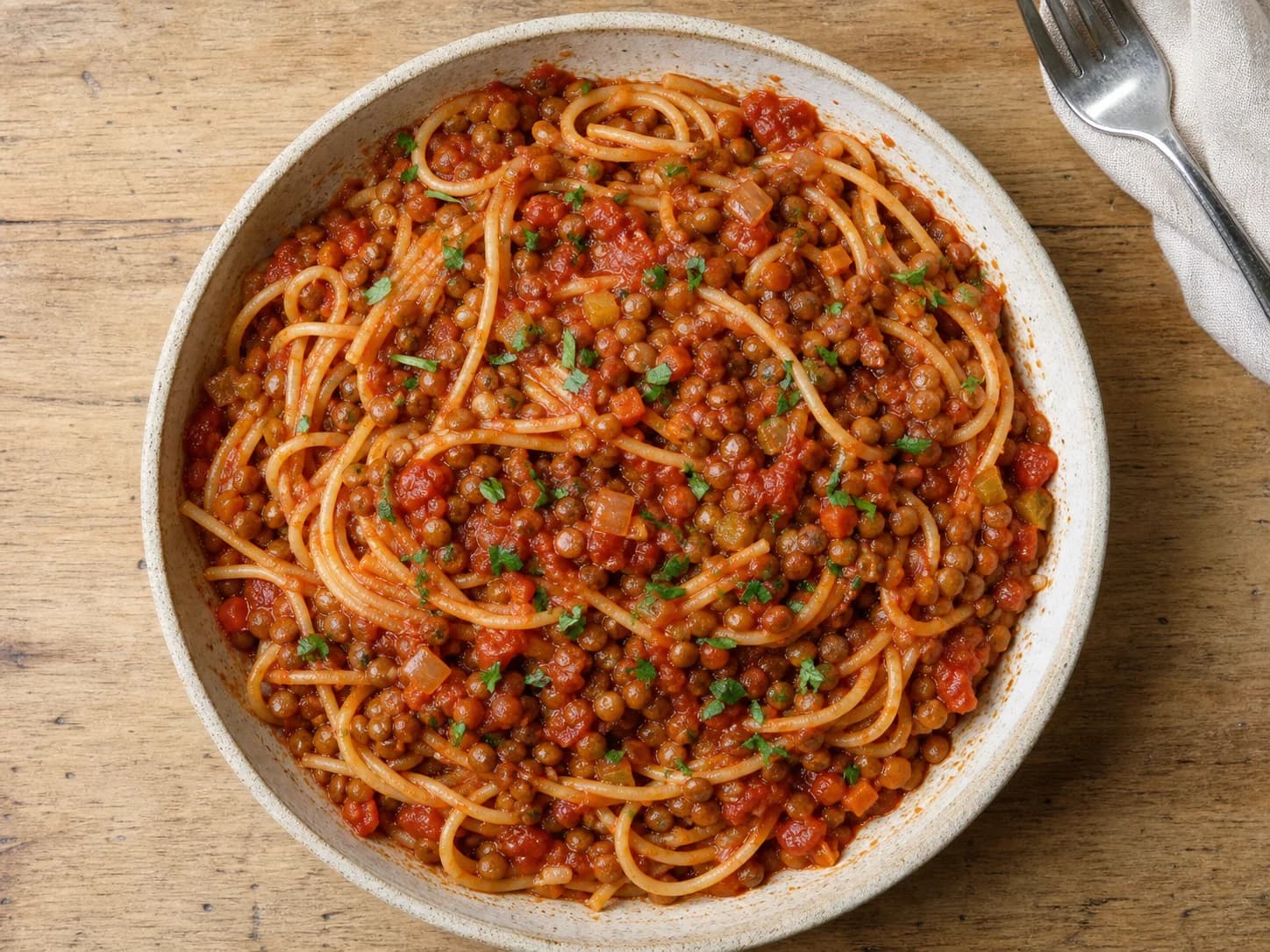 Overhead view of lentil tomato bolognese & spaghetti, served as a family dinner.