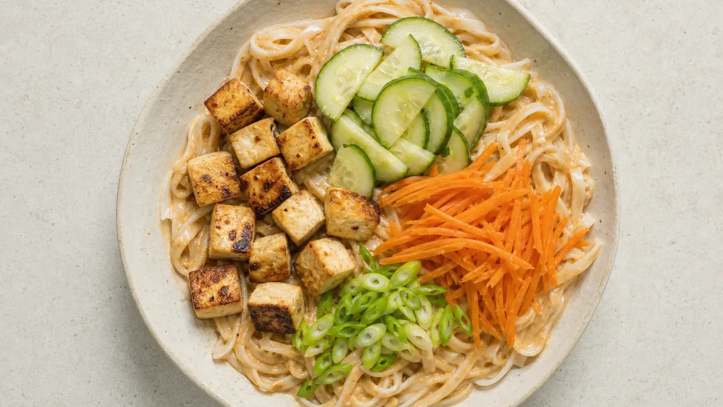 Overhead view of peanut-tofu rice noodles & cucumber, served as a family dinner.