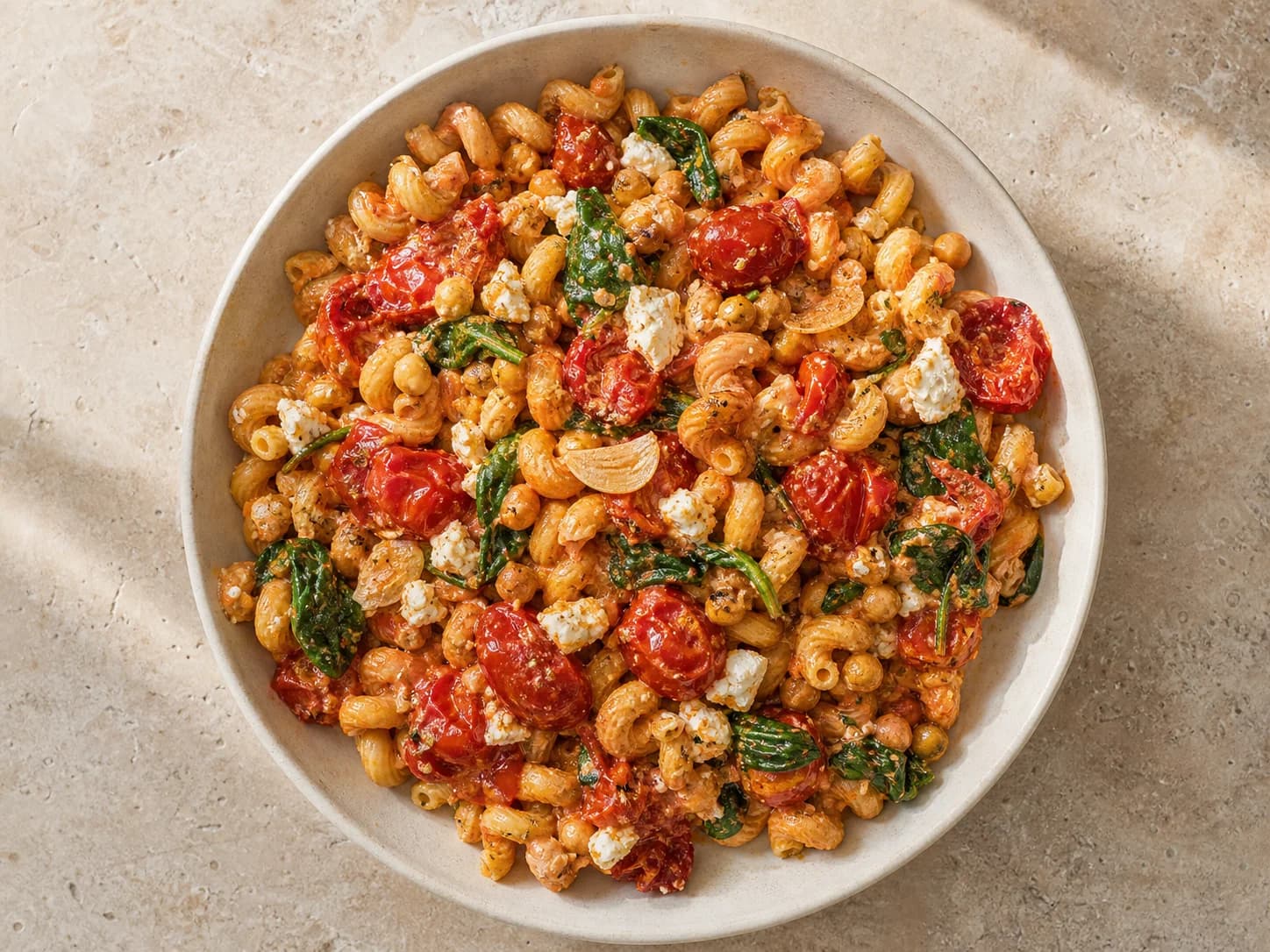 Overhead view of roasted tomato-feta chickpea pasta, served as a family dinner.