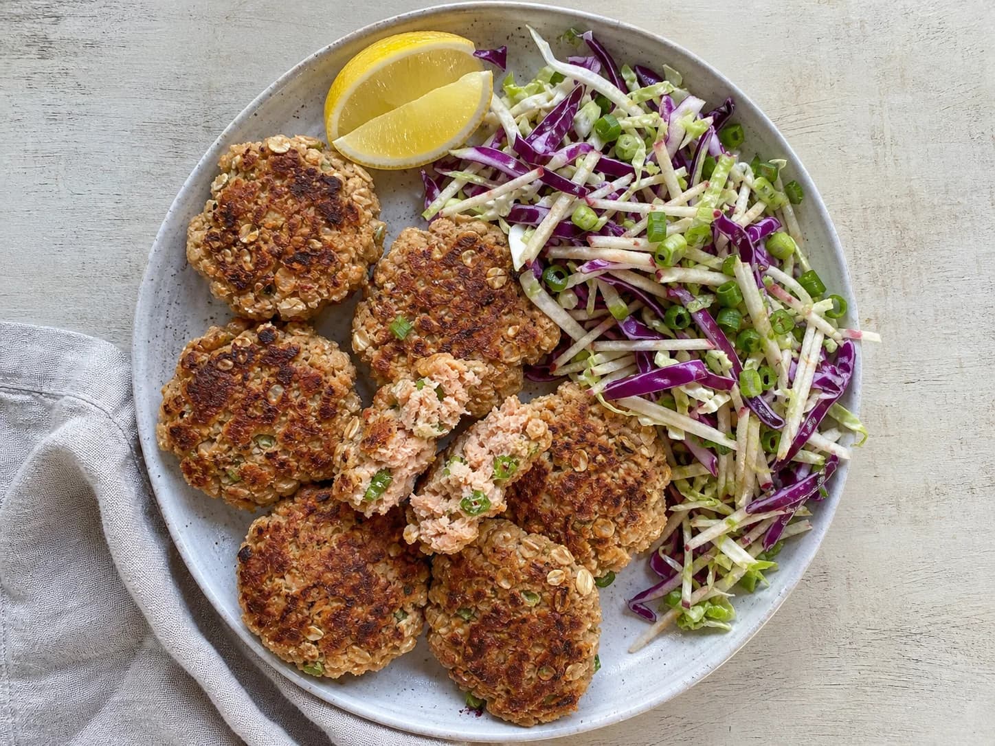Overhead view of salmon cakes & crunchy slaw, served as a family dinner.