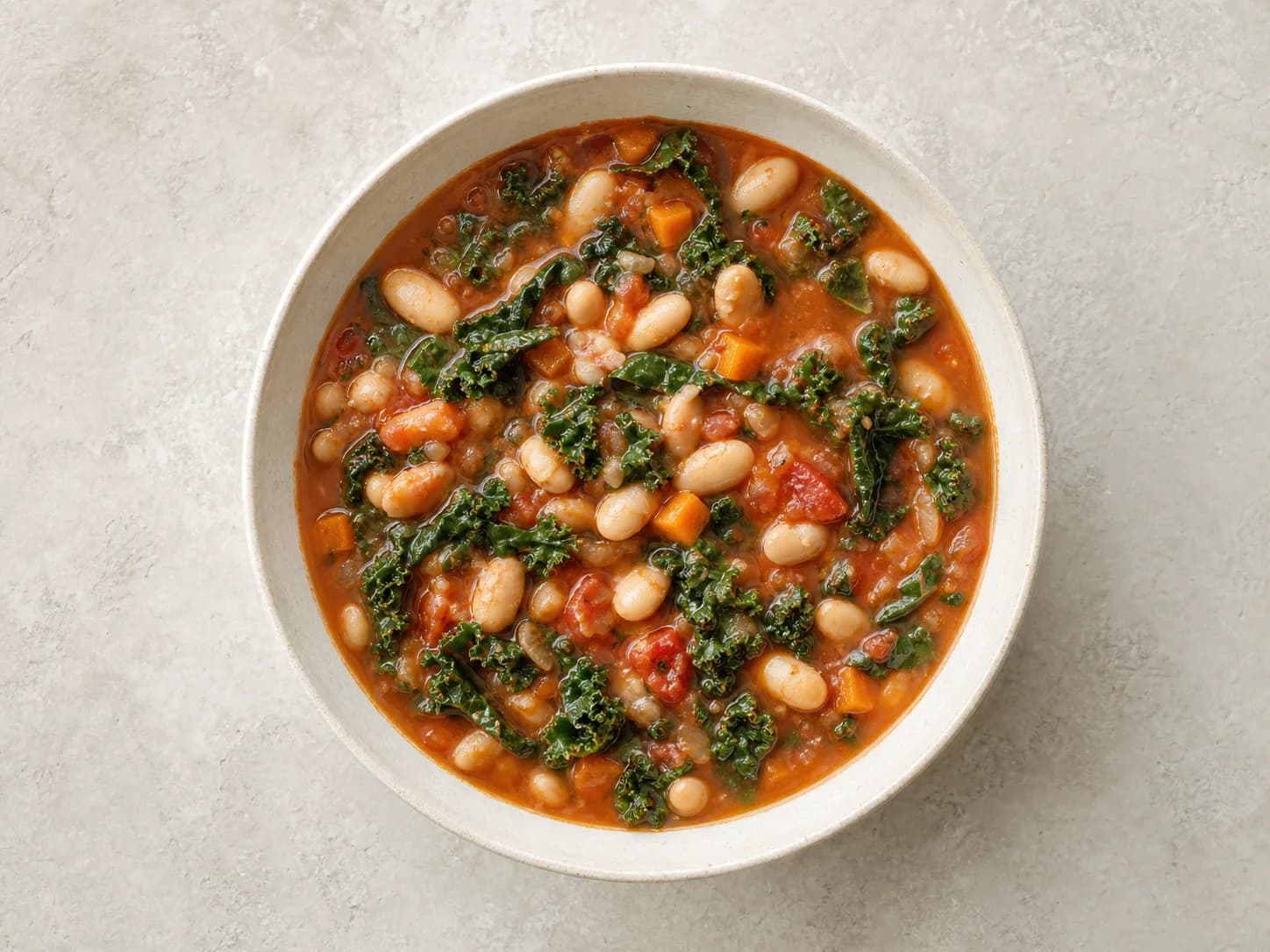 Overhead view of white-bean kale tomato soup, served as a family dinner.