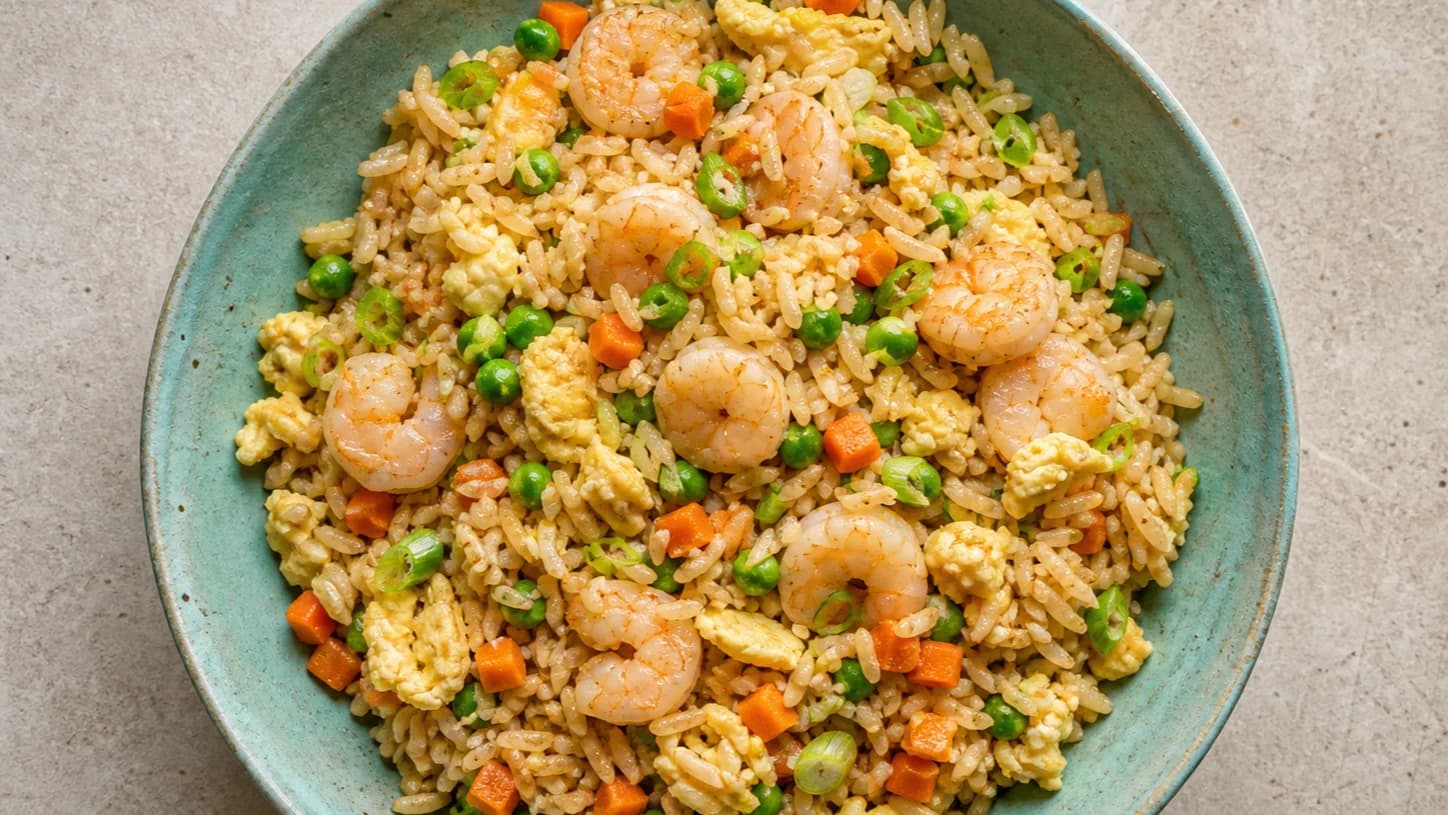 Overhead view of shrimp fried rice & vegetables, served as a family dinner.